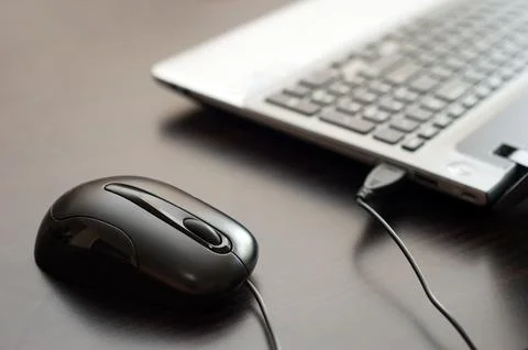 Computer wired mouse and laptop on a table close up Stock Photos