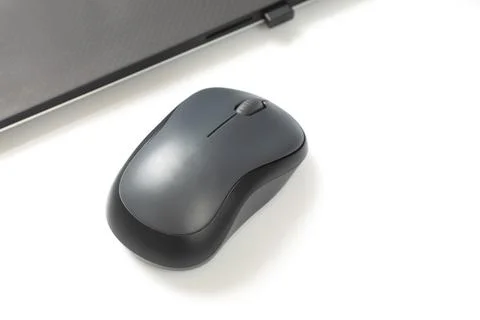 Computer wireless mouse next to a laptop on a white table close-up. electroni Stock Photos