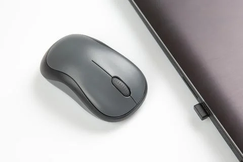 Computer wireless mouse next to a laptop on a white table close-up. electroni Stock Photos