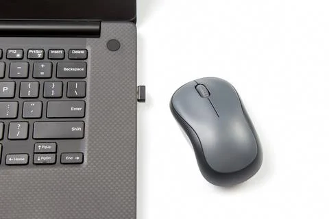 Computer wireless mouse next to a laptop on a white table close-up. electroni Stock Photos