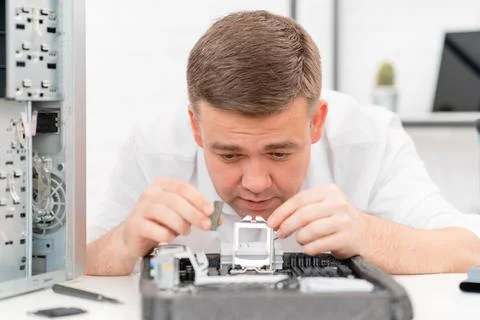 Computer workshop. professional services. man repairs motherboard and processor 写真素材
