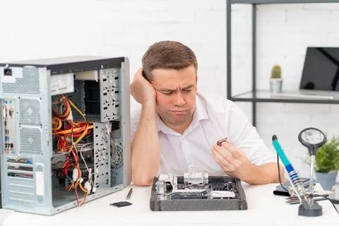 Computer workshop. professional services. sad repairman with a processor in hand 写真素材
