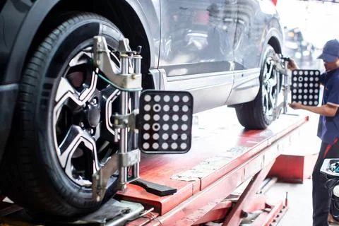 Computerized wheel alignment sensors attached to car wheels in service garage Stock Photos