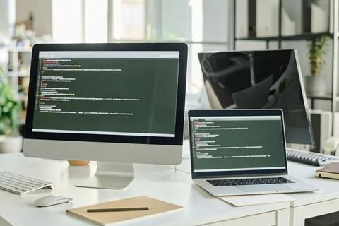 Computers with codes on table at office Stock Photos
