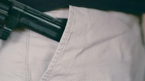 Concealed Weapon: Close-up of Revolver Being Placed in Pocket. Grey Casual Pants Stock Footage 284169977