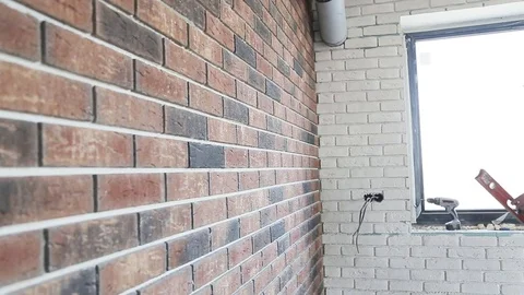 Concentraated builder in uniform holding a level against the wall indoors Stock Footage 70421659