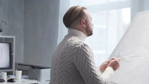Concentrated architect works in loft using drawing board. Workplace of young Stock Footage 142581034