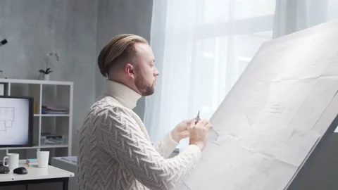 Concentrated architect works in loft using drawing board. Workplace of young Stock Footage 142587050
