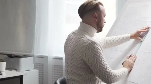 Concentrated architect works in loft using drawing board. Workplace of young Stock Footage 142892695