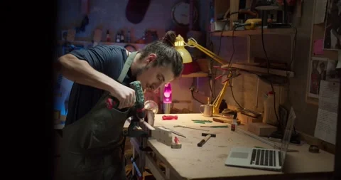 Concentrated artisan male using electrical drill working with wooden guitar arm Stock Footage 137242474
