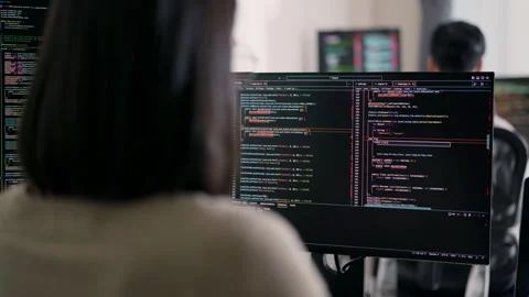 Concentrated Asian female developer debugging software on a multi-monitor. Video stock 310589132