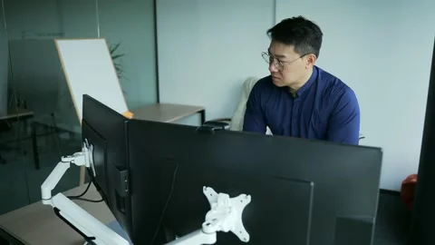 Concentrated asian programmer, financial analyst or trader working at computer  Stock Footage 218621926