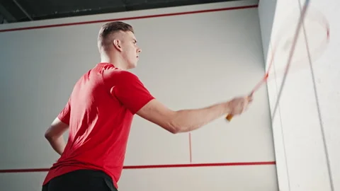 Concentrated athlete hits ball with racket in squash court Stock Footage 220960407