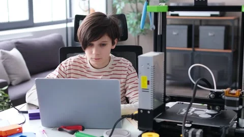 Concentrated Boy Doing Homework With Laptop And 3D Printer Stock Footage 266786826