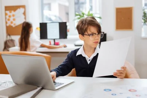 Concentrated boy reading a document in a classroom Stockfoto's