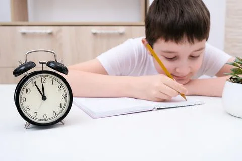 A concentrated boy writing in a textbook, exercisebook, a schoolboy doing his Stock Photos