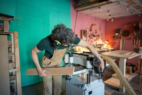 Concentrated carpenter processing wooden block on planer thicknesser jointer Stock-Fotos
