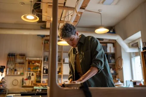 Concentrated carpenter working on making a table, using clamping brackets and Stock Photos