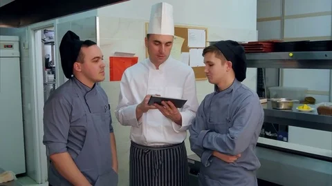 Concentrated chef showing his trainees something on digital tablet 스톡 동영상 72321383