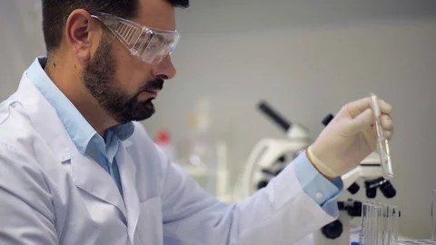 Concentrated chemist dropping liquid into several test tubes Stock Footage 80356538