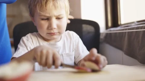 Concentrated child cutting fruit with a knife Stock Footage 319154586