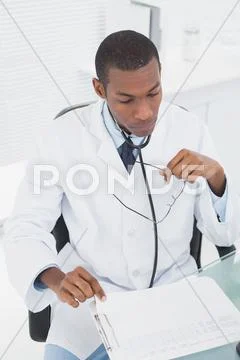 Concentrated doctor reading a note at medical office Stock Photos