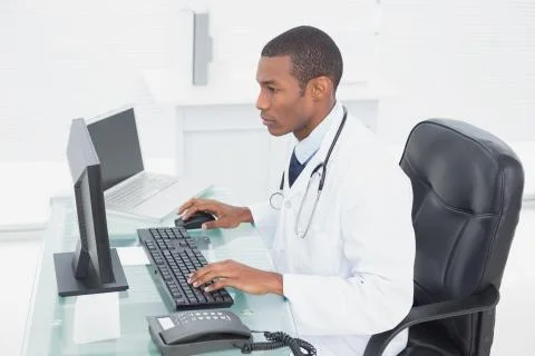 Concentrated doctor using computer at medical office Stock Photos