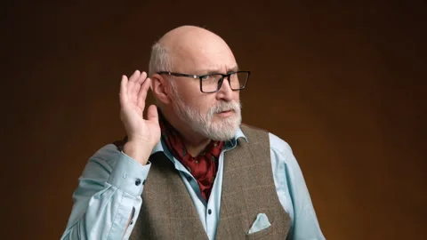 Concentrated Elderly Man Cupping Ear to Hear on Warm Brown Background Stock Footage 262858453