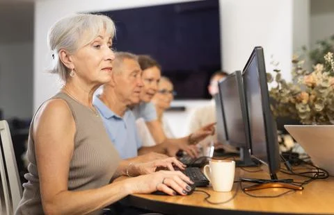 Concentrated elderly woman using computer at internet cafe Fotos de archivo