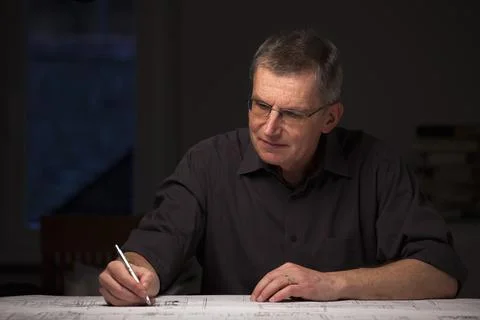 Concentrated engineer or architect in dark shirt working at home by night Stock Photos