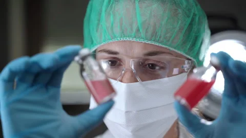 Concentrated female chemist in protective gloves, face mask and glasses holding Stock Footage 151527770