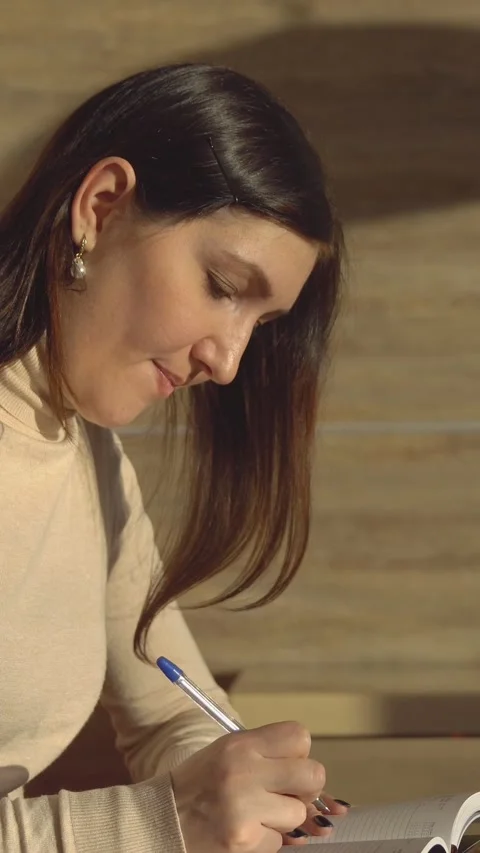 Concentrated female student taking notes in a notebook, diligently studying for Stock Footage 341678462