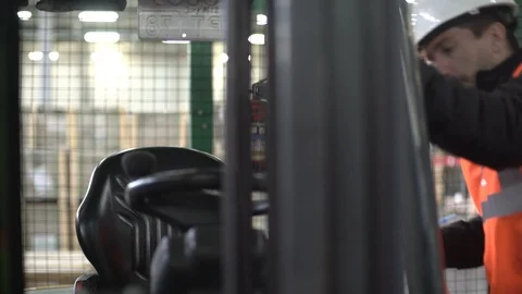 Concentrated forklift driver comes inside, checking the tablet inside machine. Stock Footage 101235114