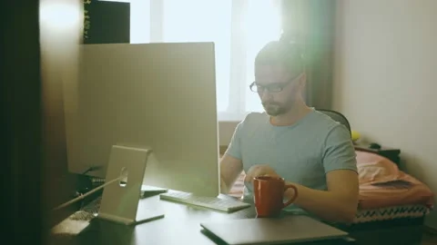 Concentrated freelancer guy in glasses looks at computer monitor, works at home Stock Footage 237240545