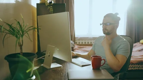Concentrated freelancer guy in glasses looks at computer monitor, works at home Stock Footage 237533728