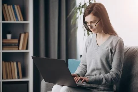 Concentrated girl working on laptop while staying at home Stock Photos