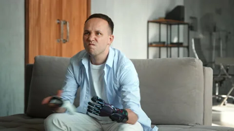 Concentrated guy with hi tech hand prothesis loses game Stock Footage 157348702