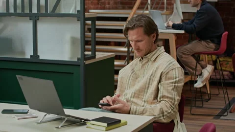 Concentrated IT Specialist Looking at Phone Screen in Modern Coworking Space Stock Footage 319998611
