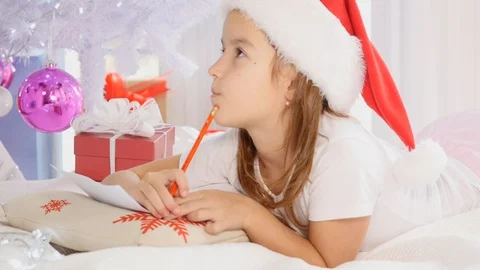 Concentrated kid is involved in the process of thinking over all her wishes and Video stock 118375022