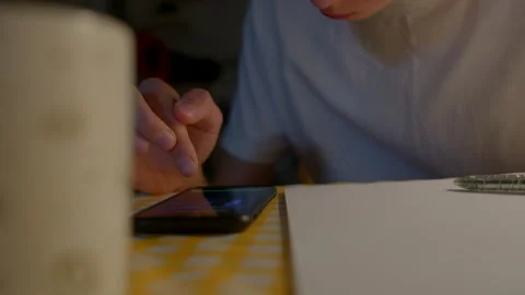 Concentrated learner working on formulas with phone and soft lighting Stock Footage 324592123