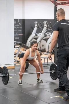 Concentrated lifter pulls the bar guided by her coach. 스톡 사진
