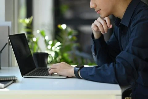 Concentrated male programmer writing program code on laptop computer in the Stock Photos