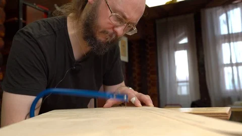 Concentrated man with beard cuts brown wooden veneer Stock Footage 126714617