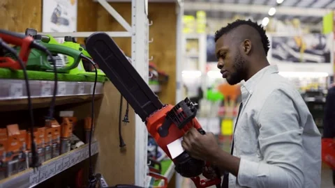 Concentrated man examining chainsaw at a hardware store Video stock 171656005
