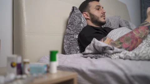 Concentrated man playing video games in bed. Nightstand with medicines and pills Video stock 129305711