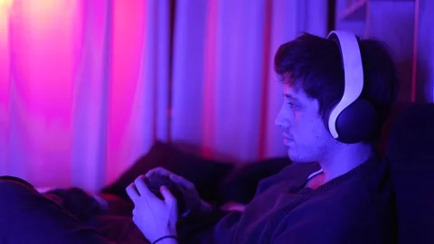A concentrated man playing video games smiling with headphones looking at the tv Stock Footage 199127947