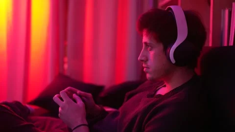 A concentrated man playing video games smiling with headphones looking at the tv Stock Footage 199128430