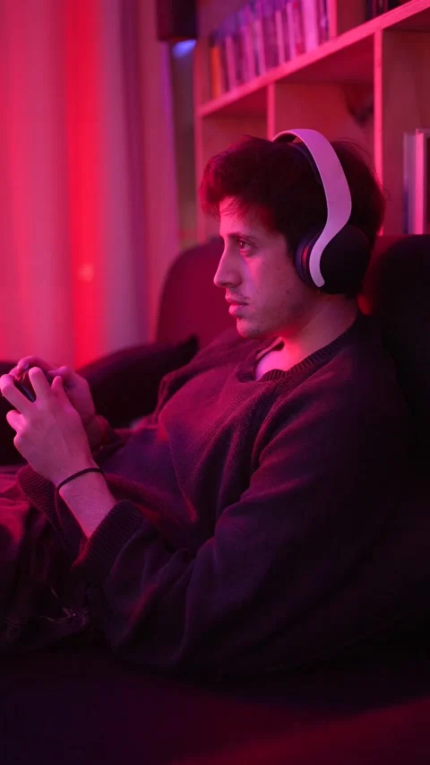 A concentrated man playing video games smiling with headphones looking at the tv Stock Footage 199129153