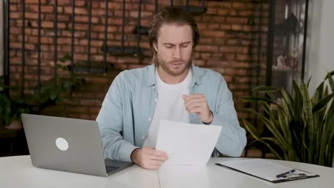 Concentrated man reading contract sitting at the desk. Employee reading a Stock Footage 196011533
