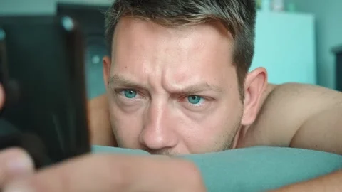 Concentrated man scrolling smartphone in bed in the morning surfing internet Stock Footage 252131302